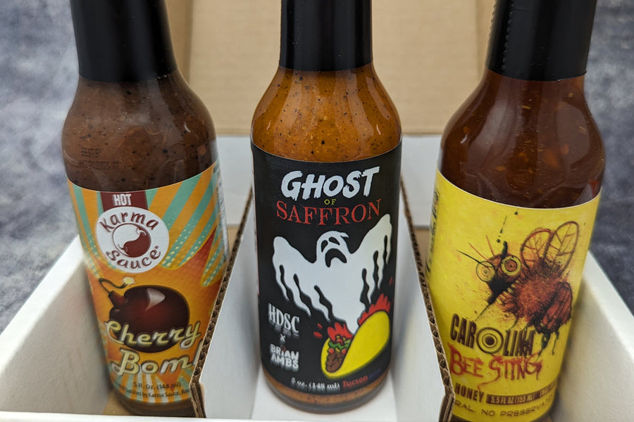 Three small-batch hot sauce bottles from a SCOVILLED monthly subscription box