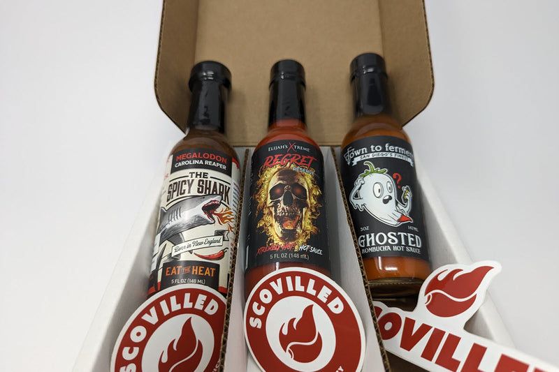 Open SCOVILLED subscription box packed with three extra hot sauces: The Spicy Shark Megalodon Carolina Reaper, Elijah's Xtreme Regret Reserve, and Grown to Ferment Ghosted kombucha hot sauce